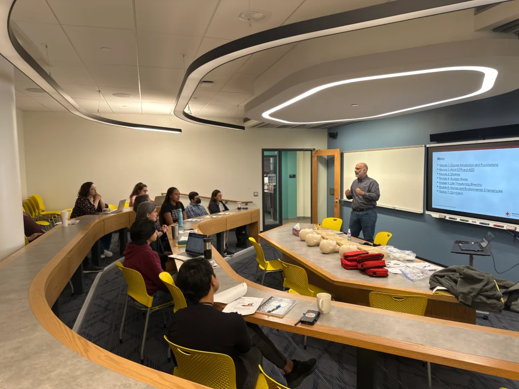 Safety instructor teaching a group of young individuals about CPR and AED life saving techniques